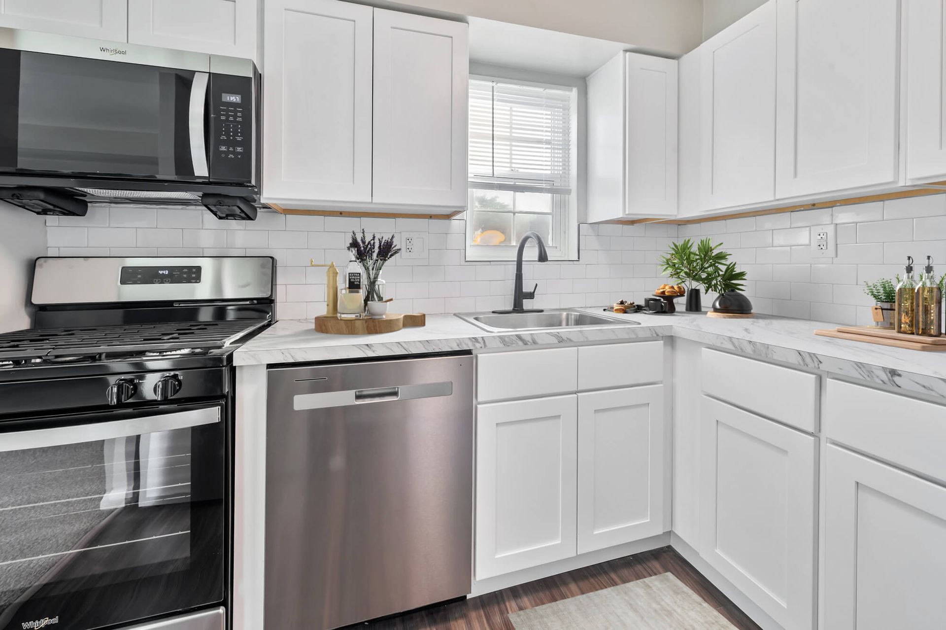 Bright, modern white kitchen with stainless steel appliances and marble countertops.