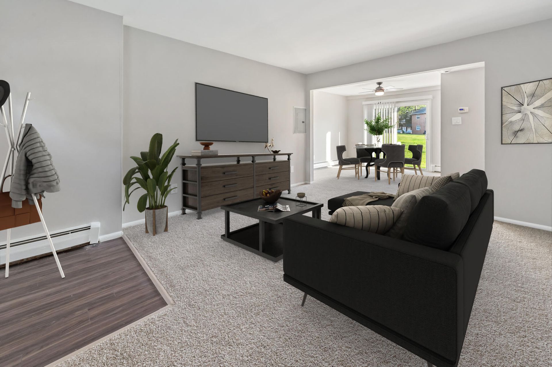 Living room with a black sofa, coffee table, TV, and an adjacent dining area.
