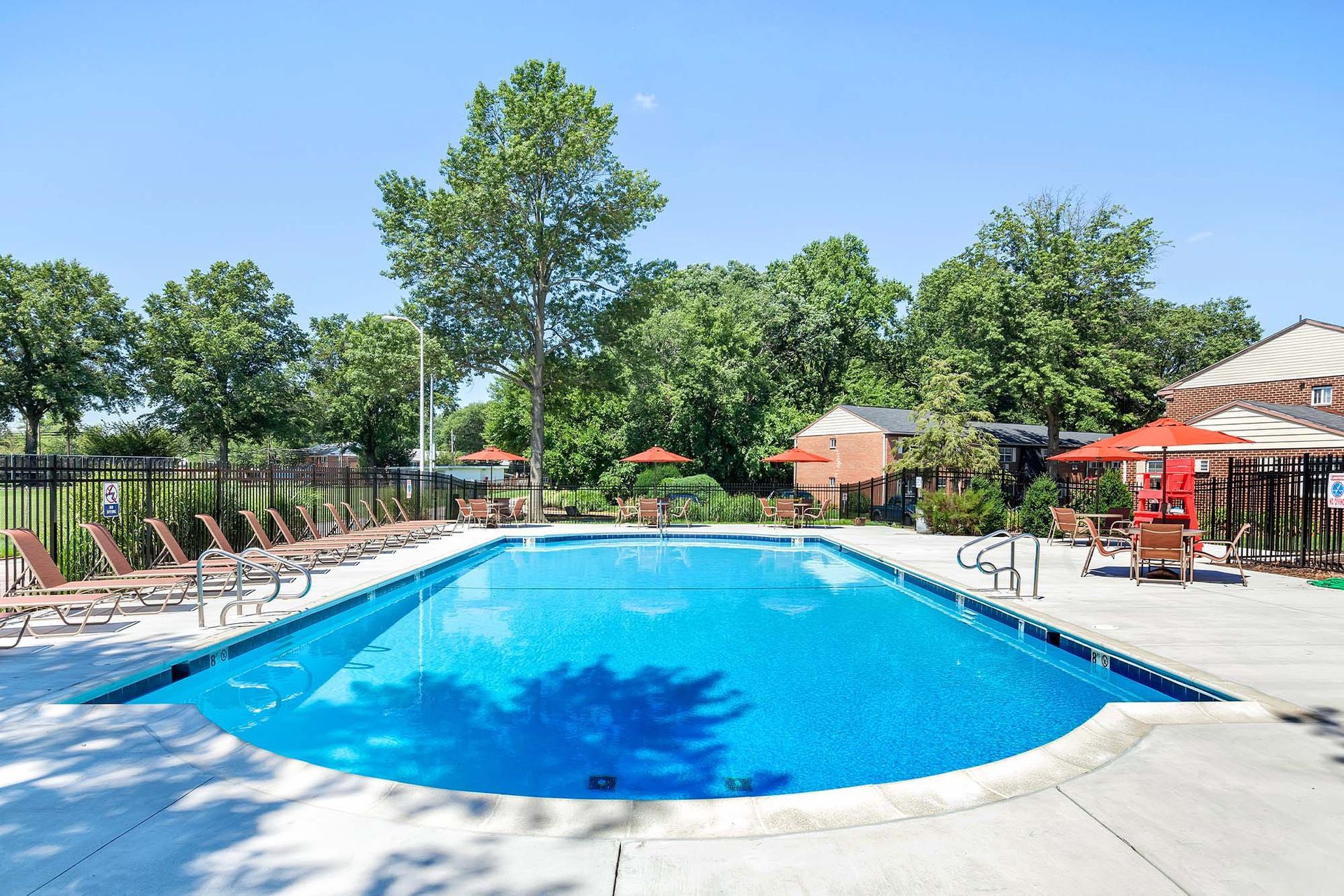 Swimming pool with blue water and surrounding lounge chairs under a sunny sky.