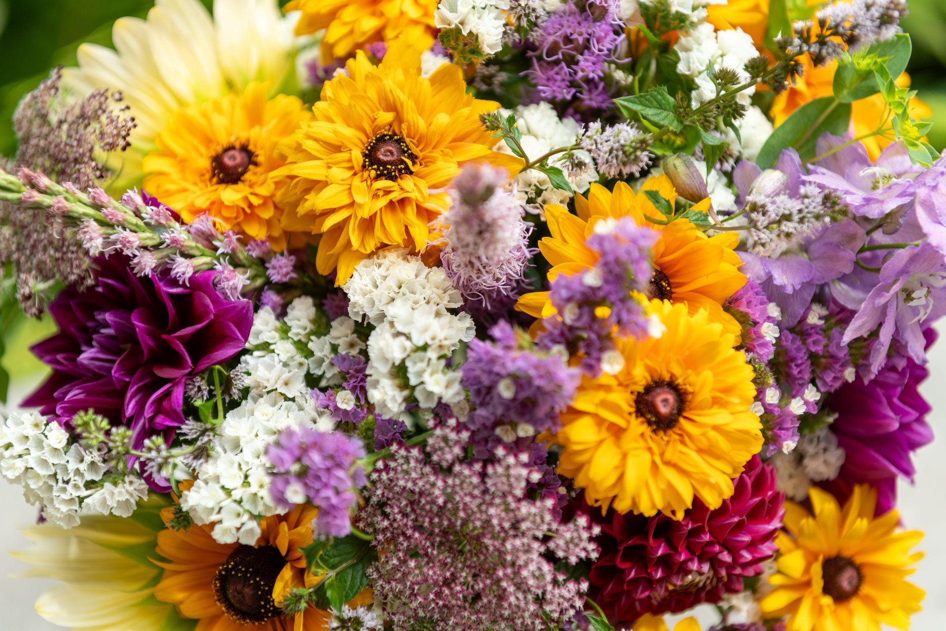 Colorful bouquet of yellow, purple, and white flowers in a dense floral arrangement