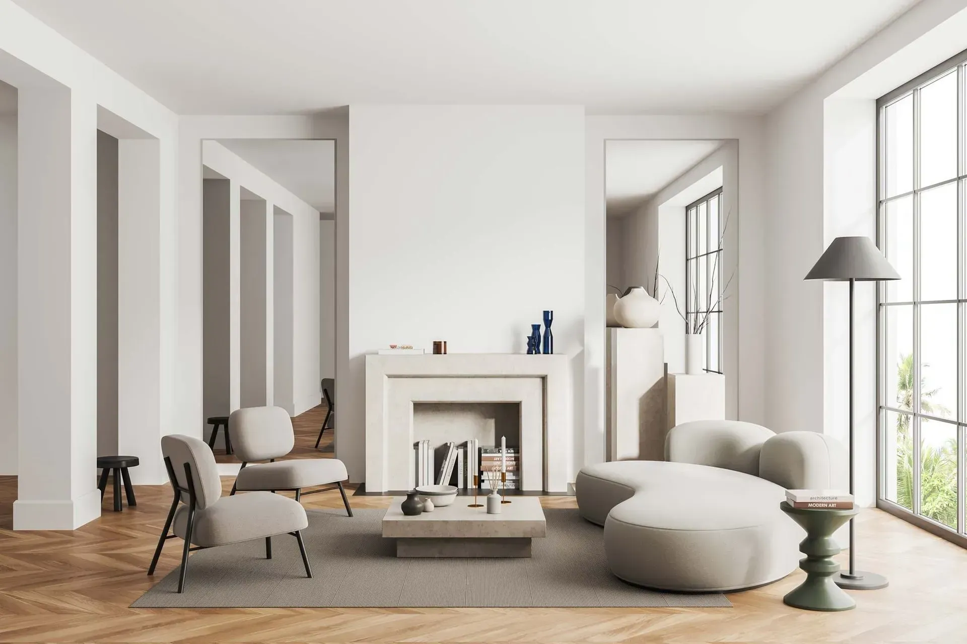 Ein minimalistisches Wohnzimmer mit Steinkamin, beigefarbenen Sesseln, einem geschwungenen Sofa und einer hohen Stehlampe.