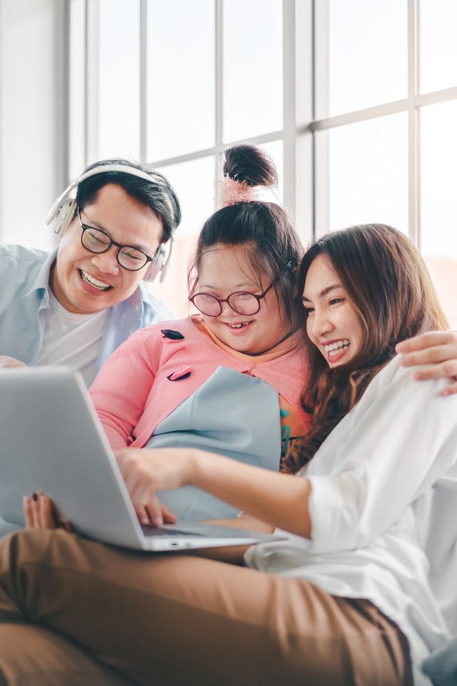 Family Smiling, Gathered Around Laptop, Indoors — Sonke Support Pty. Ltd. in Maroochydore, QLD