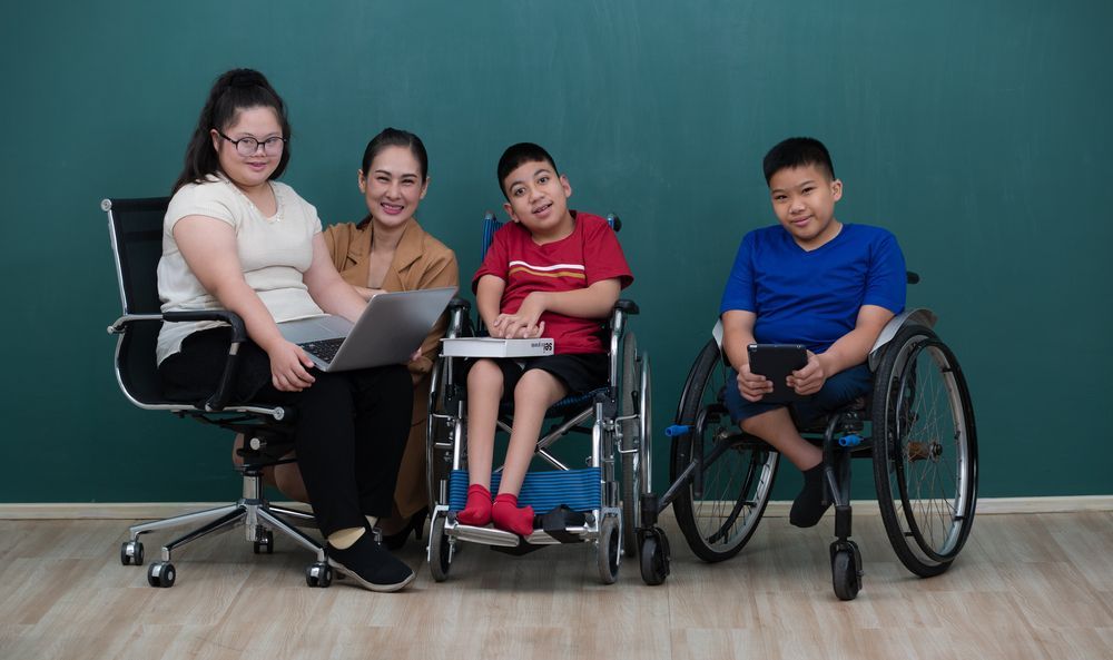 Woman With a Laptop Sits With Three Children in Wheelchairs — Sonke Support Pty. Ltd. in Noosa Heads, QLD