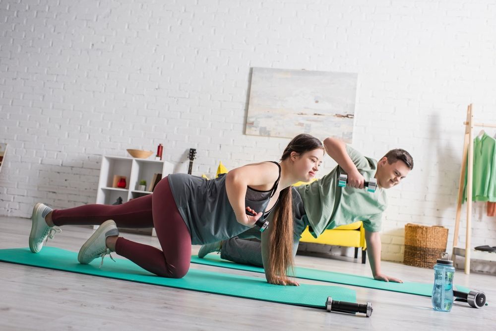 Two People Exercising on Yoga Mats, Lifting Weights Indoors — Sonke Support Pty. Ltd. in Noosa, QLD