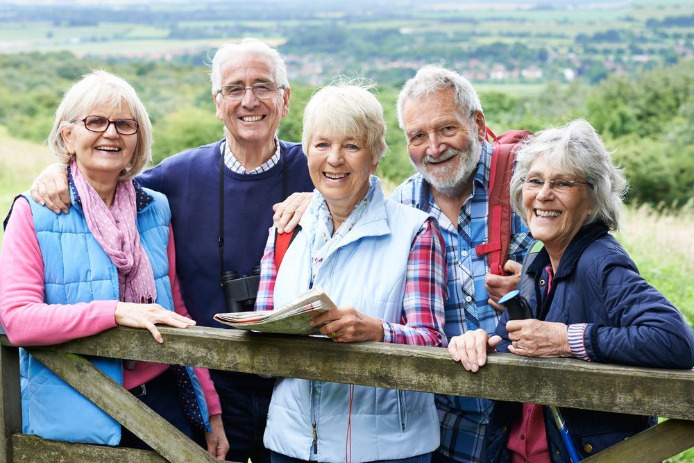 Group of Five Smiling Older Adults in Nature, Leaning on a Wooden Fence — Sonke Support Pty. Ltd. in Noosa, QLD