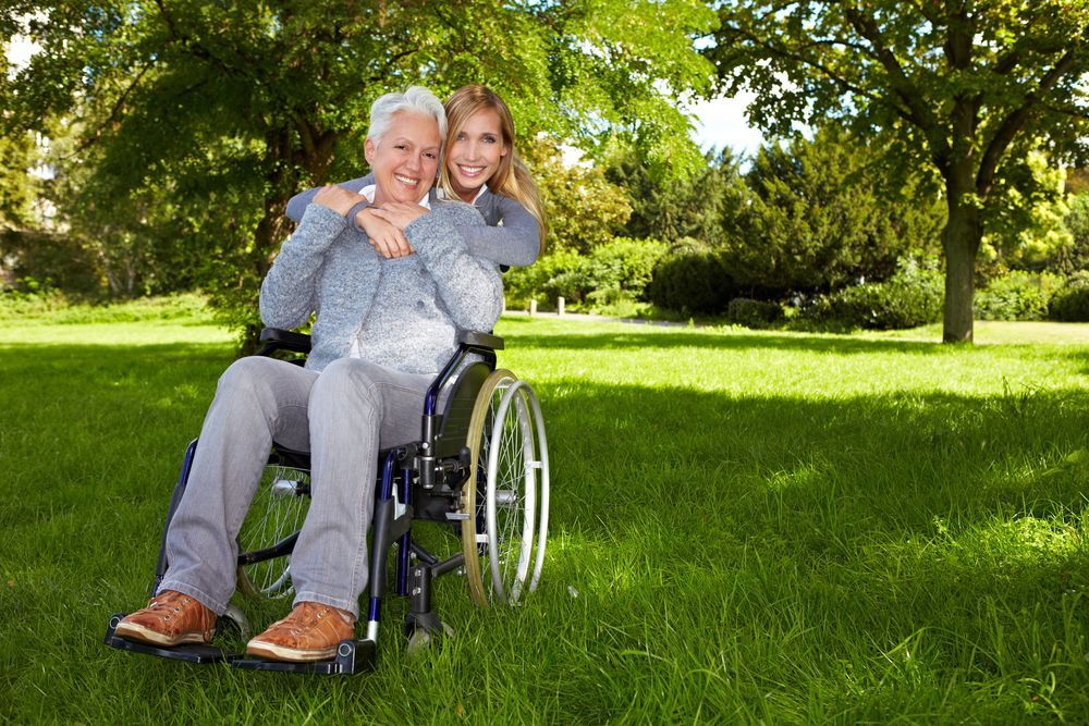 Woman in Wheelchair Embraced by Smiling Younger Woman — Sonke Support Pty. Ltd. in Noosa Heads, QLD
