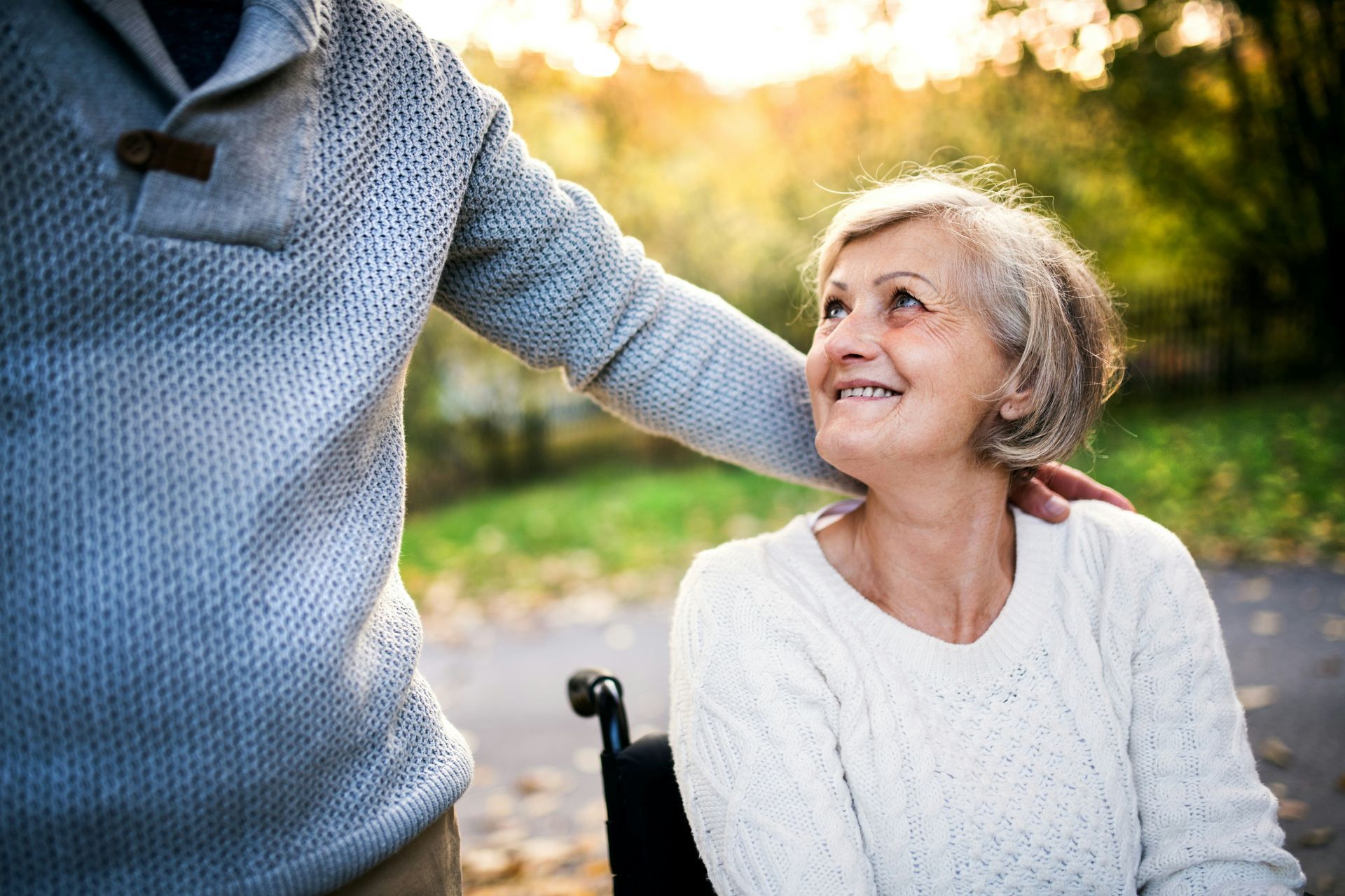 A man is walking with an elderly woman in a wheelchair.