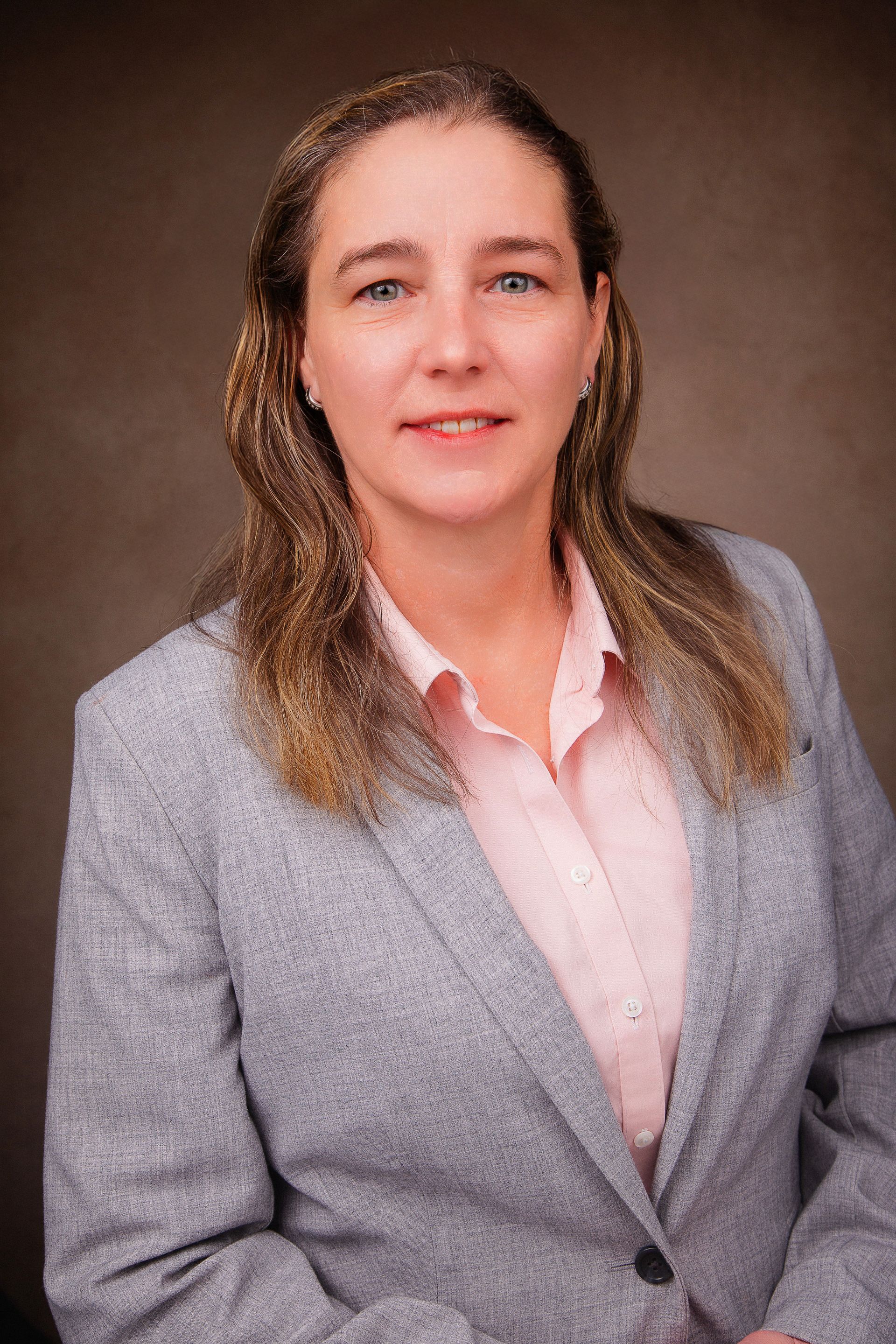 A woman is wearing a gray jacket and a pink shirt.