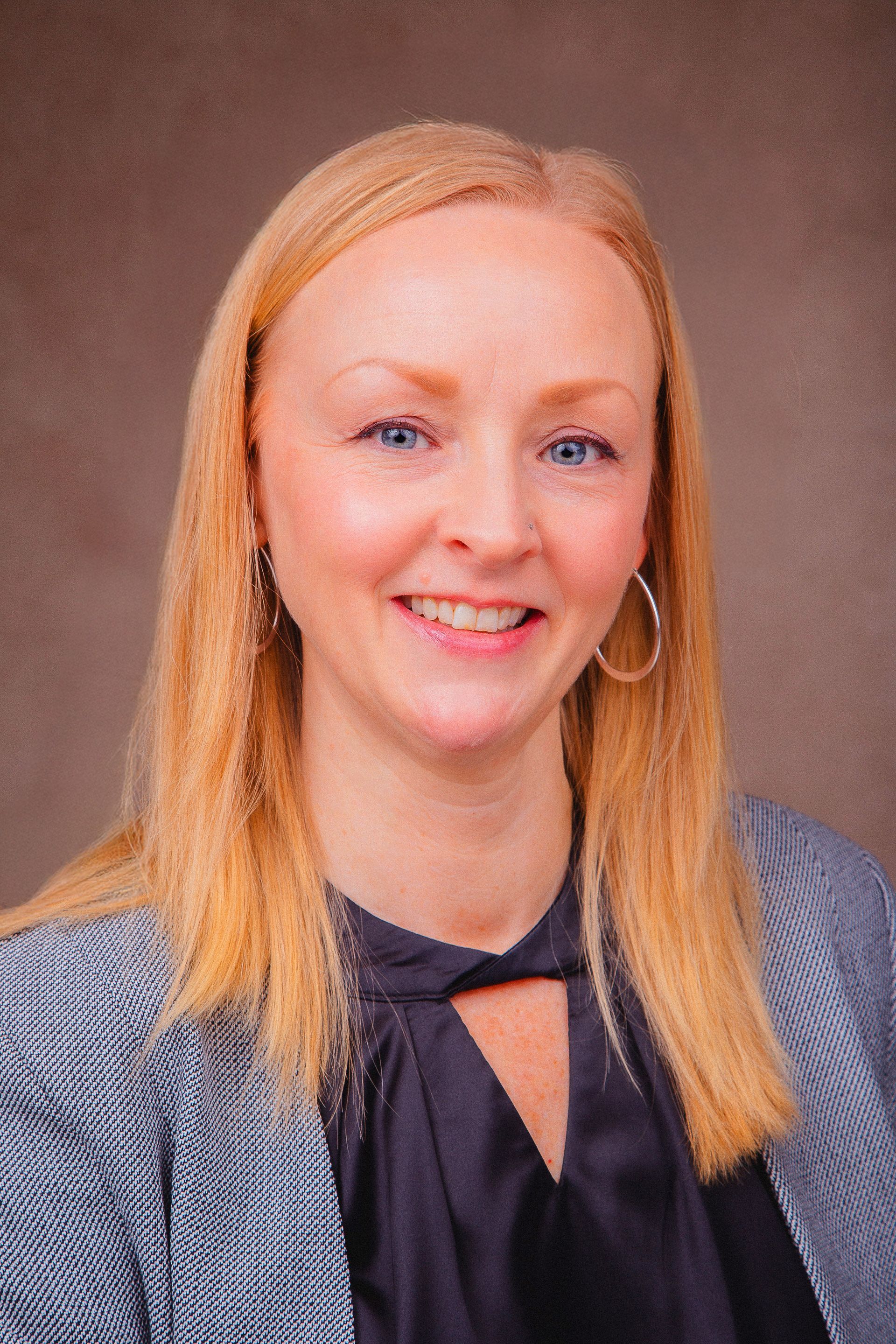 A woman with long blonde hair and blue eyes is smiling for the camera.