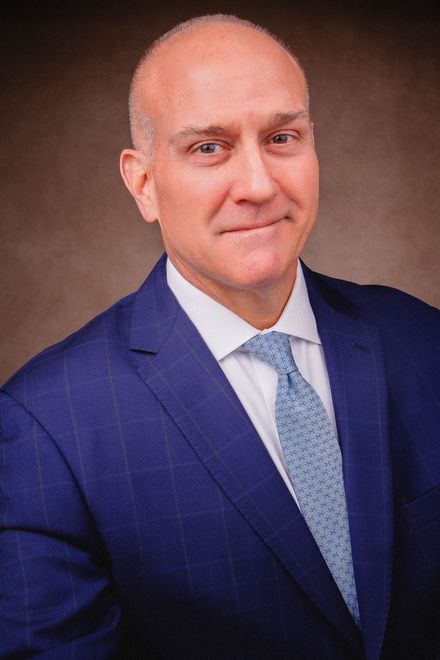 A man in a blue suit and tie is smiling for the camera.
