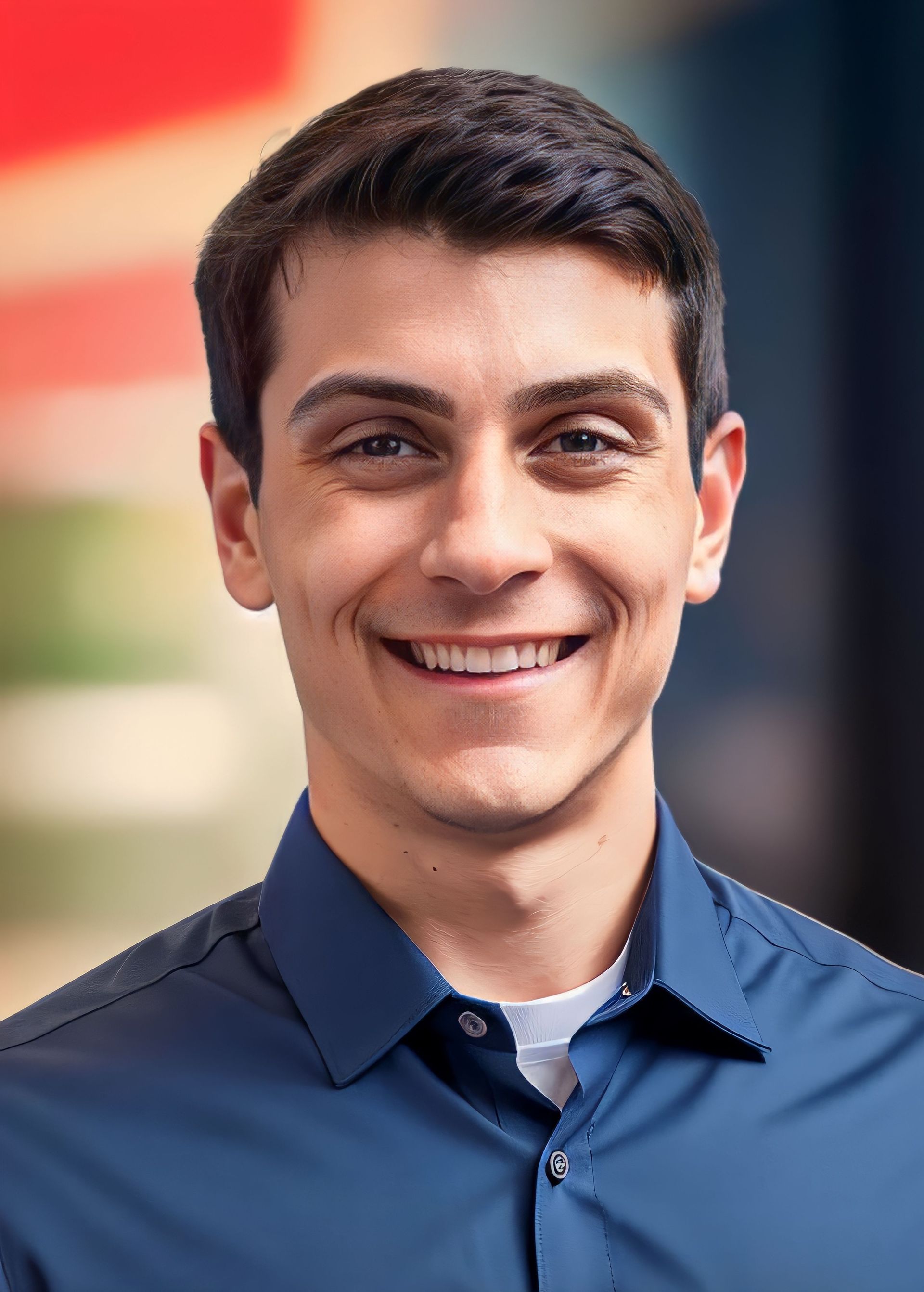 A man in a suit and tie is smiling in front of a window.