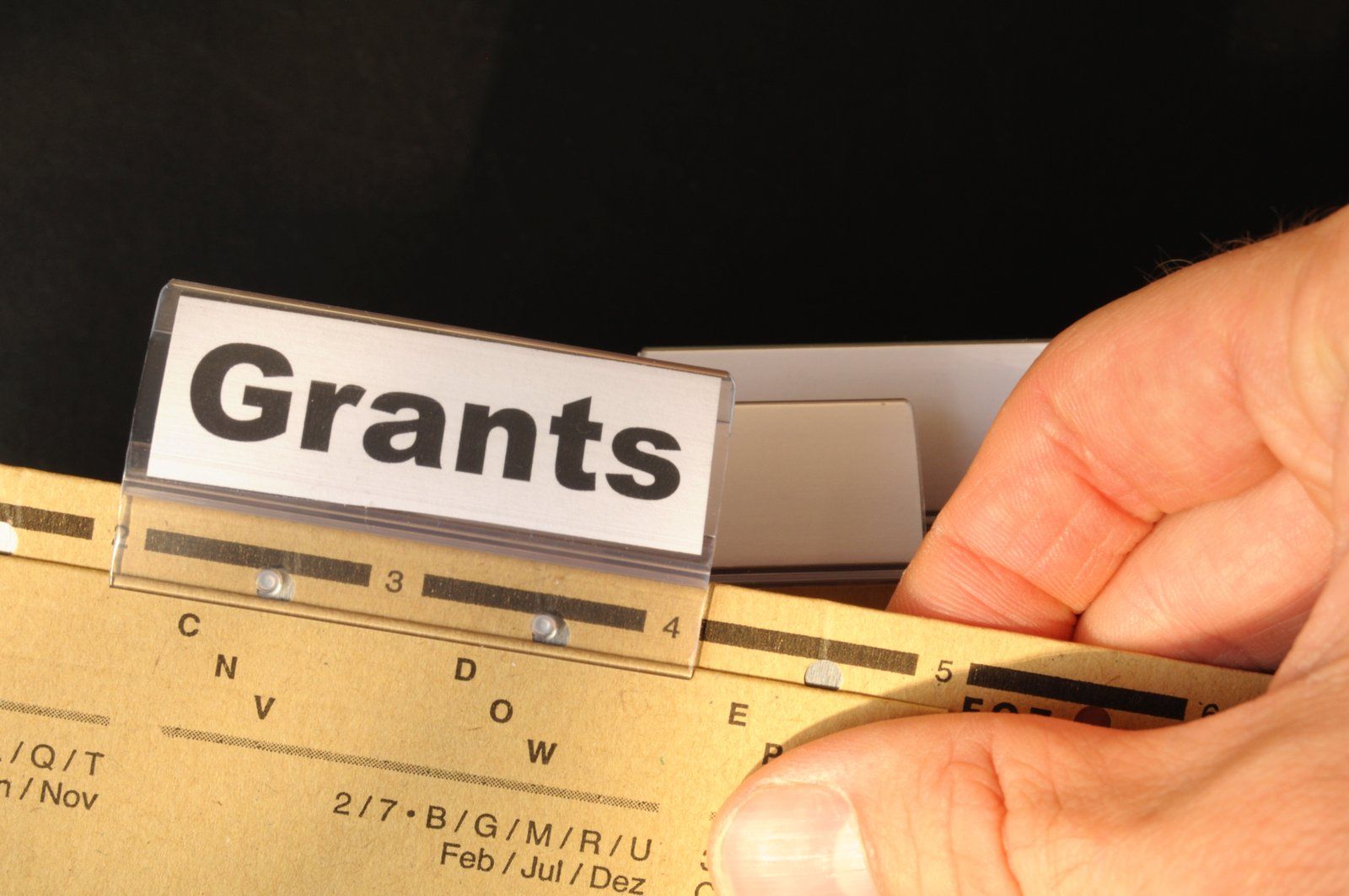 A person is holding a piece of paper that says grants