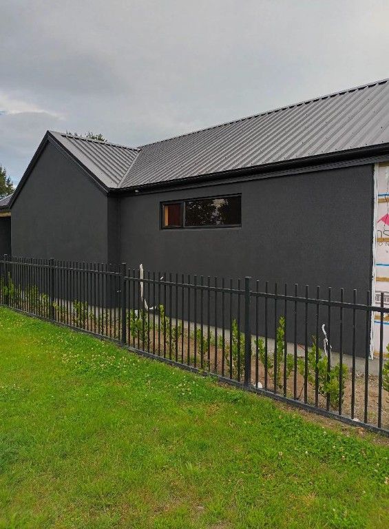A black house with a black fence in front of it.