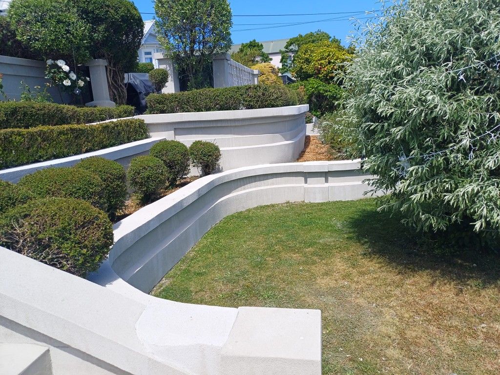 A lush green garden with a concrete wall and stairs