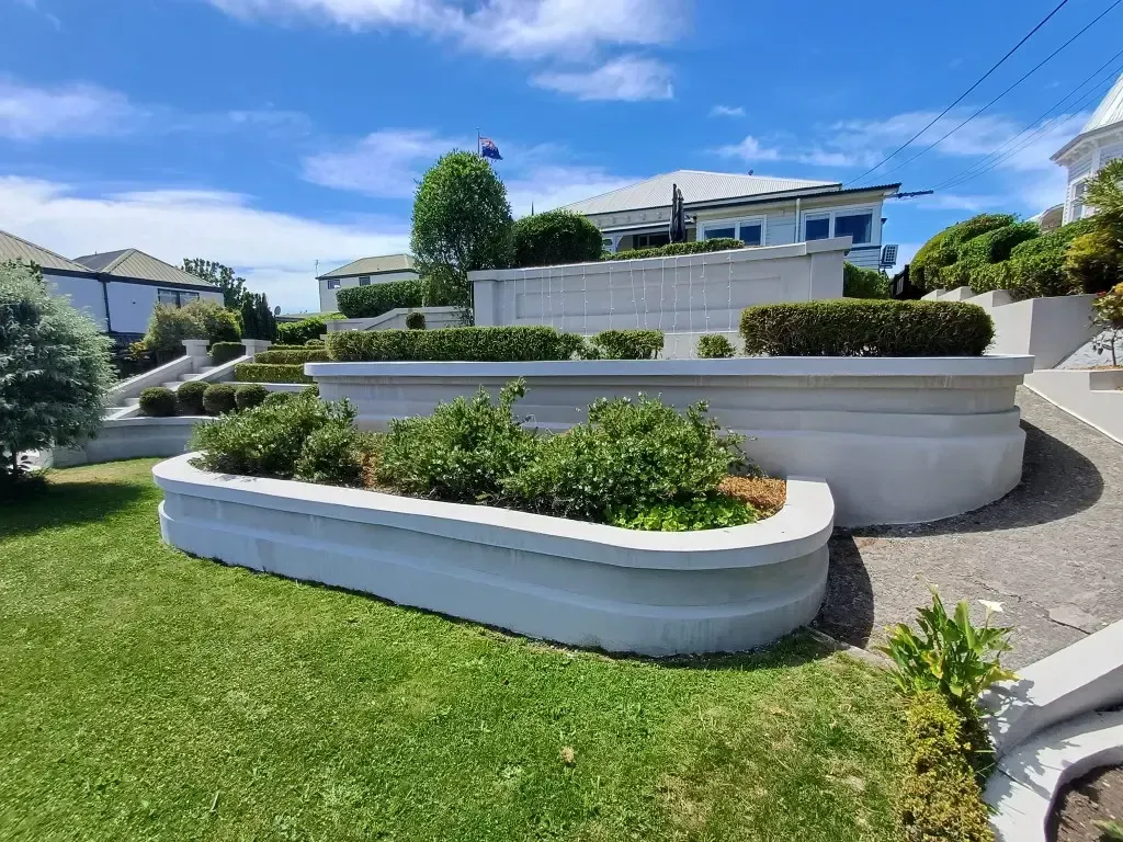 A large white house with a lot of plants in front of it.