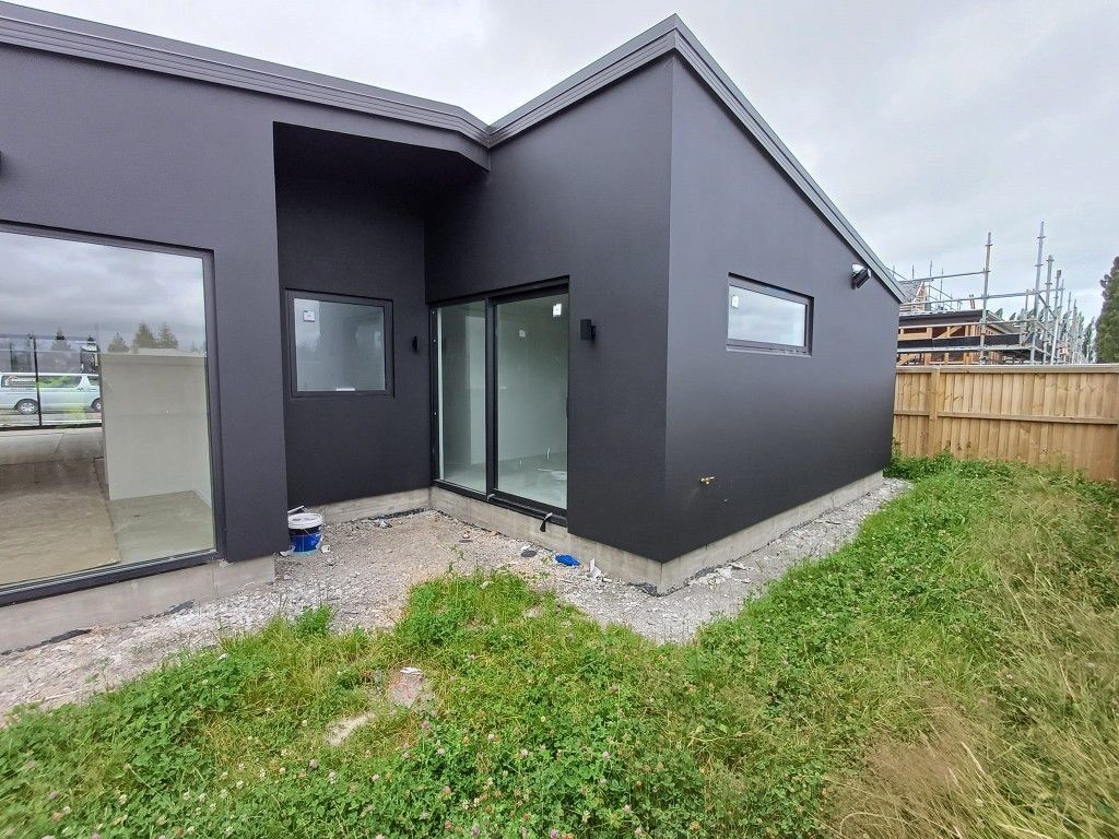 A black house with a lot of windows and a fence in the backyard.