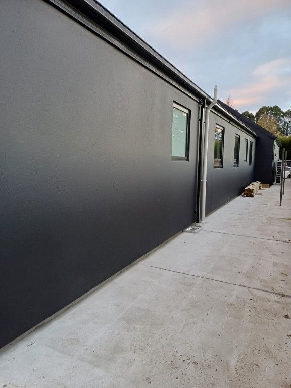 A black building with a lot of windows and a concrete walkway.