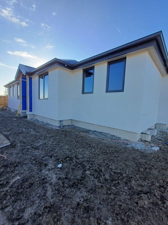A white house with a blue door is sitting on top of a dirt field.