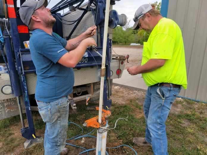 A worker providing connection service for a water well to a house water system.