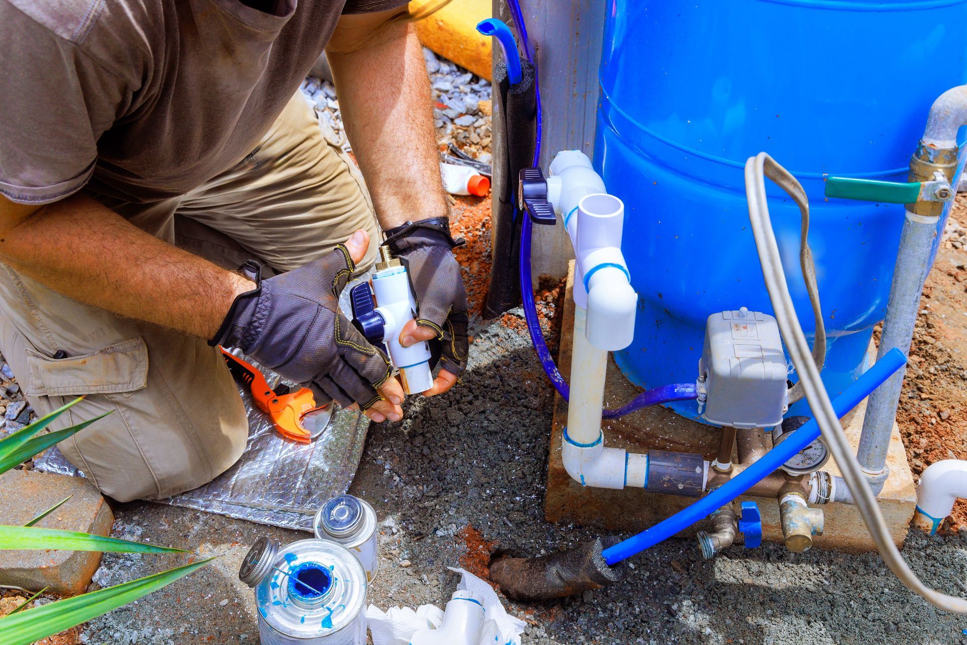 A worker providing connection service for a water well to a house water system.