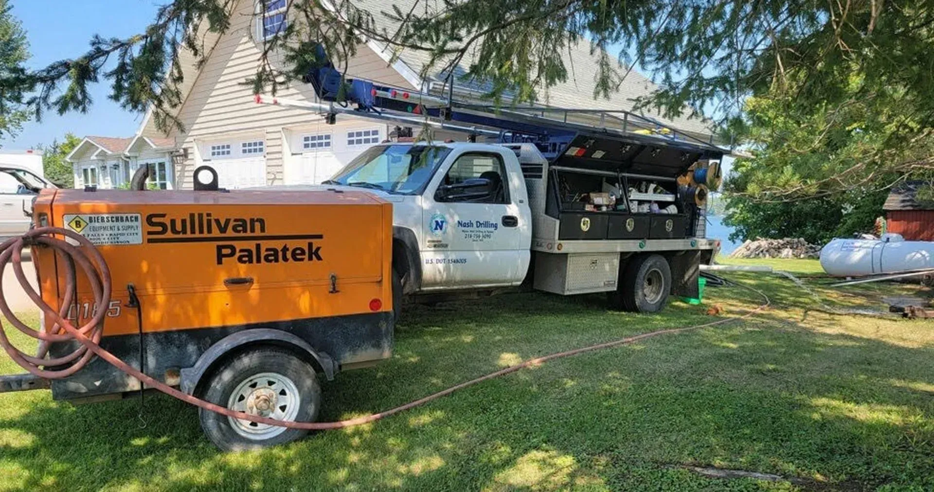 A truck with a trailer attached to it is parked in front of a house.