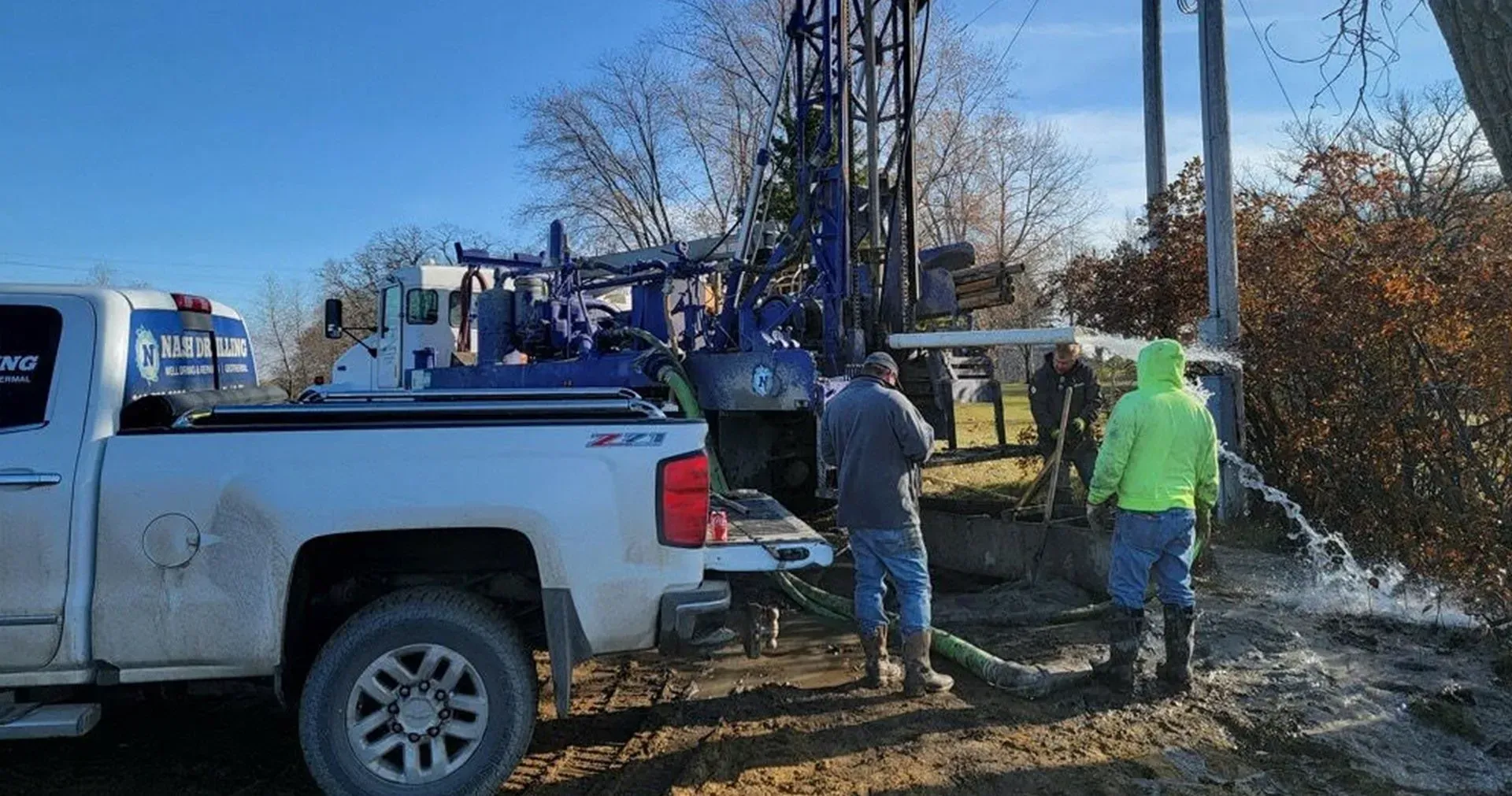 A group of men are working on a water well in a field.