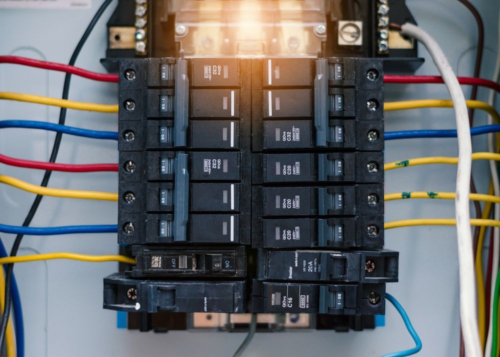 Electrical panel with multiple circuit breakers, colored wires, and glowing light.