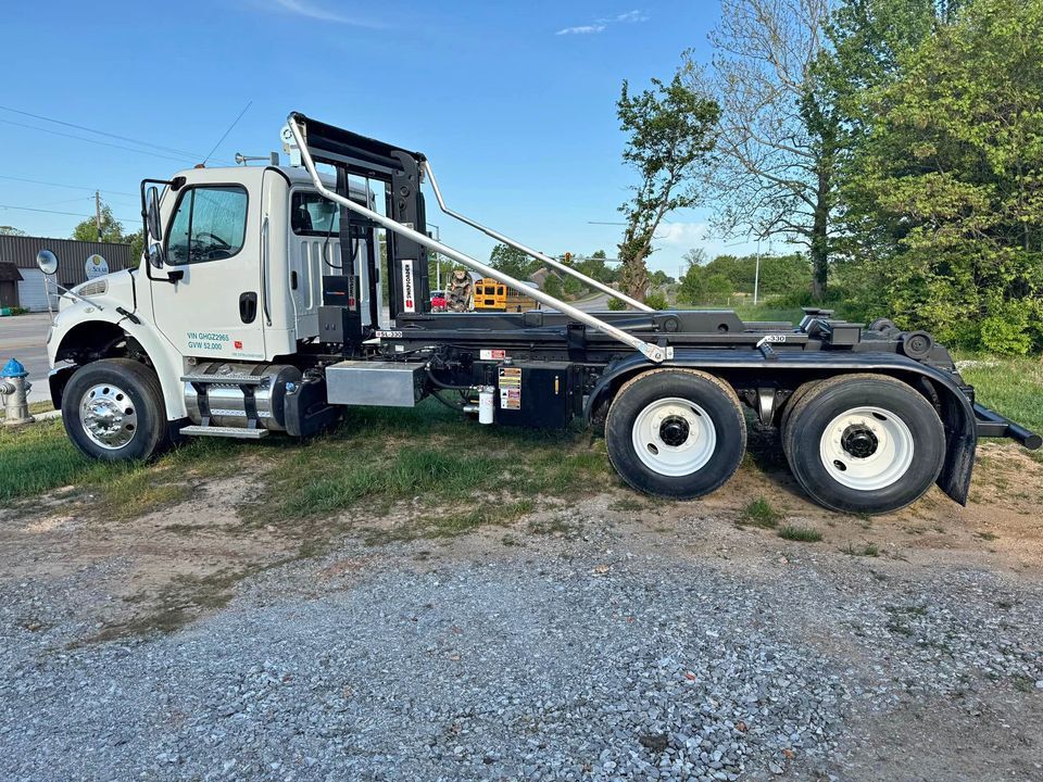 A dump truck is parked on the side of the road next to a house.