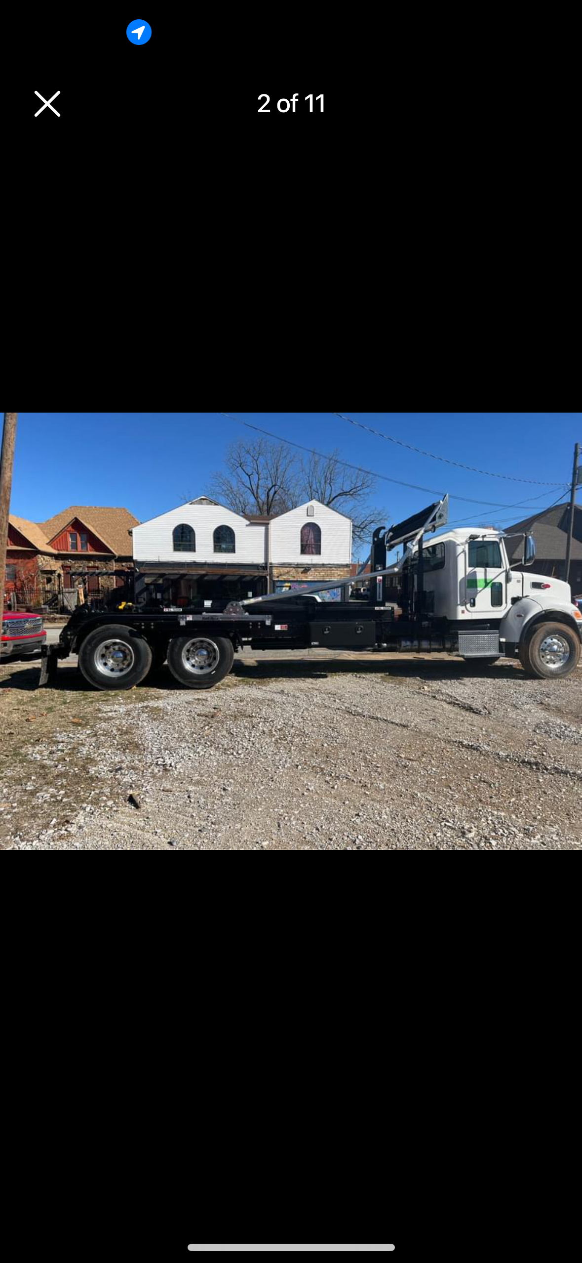 A tow truck is parked in a gravel lot next to a house.