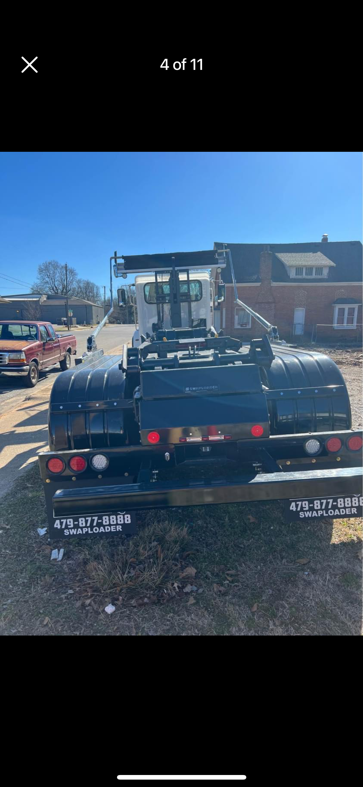 A black tow truck is parked in a parking lot next to a brick building.