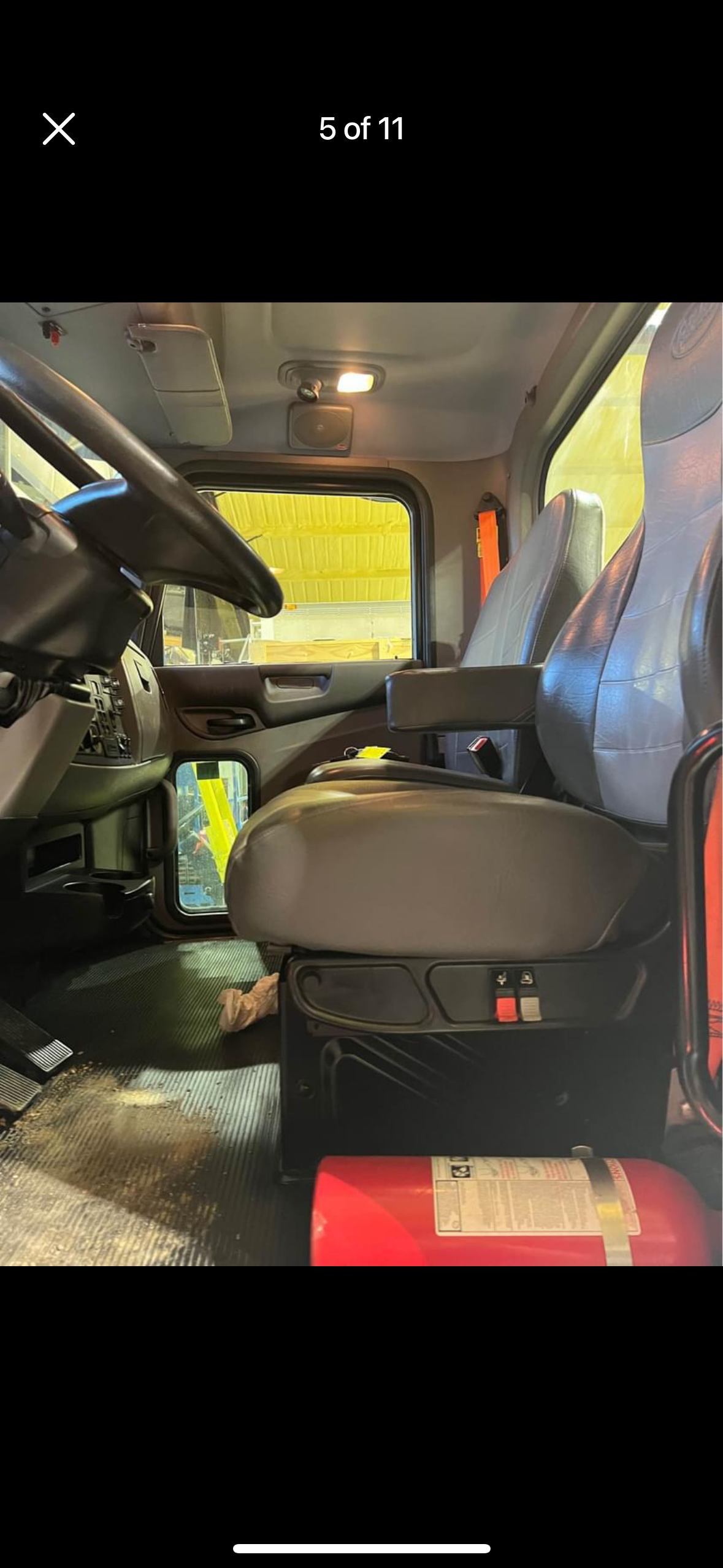 The inside of a truck with a steering wheel and seats.