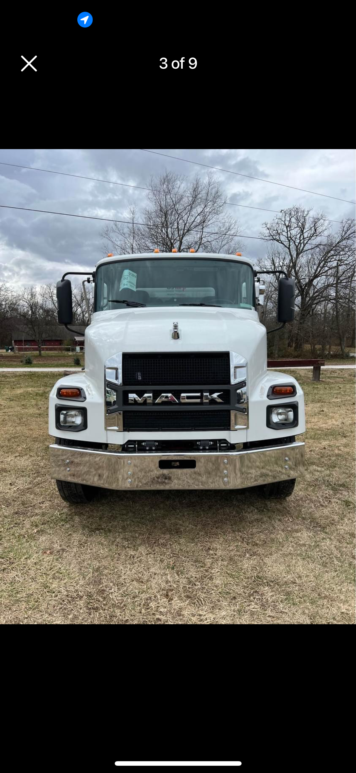 A white mack truck is parked in a grassy field.