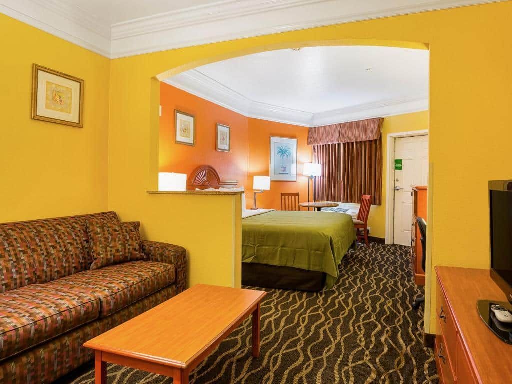 A hotel room with a couch , table , and television.