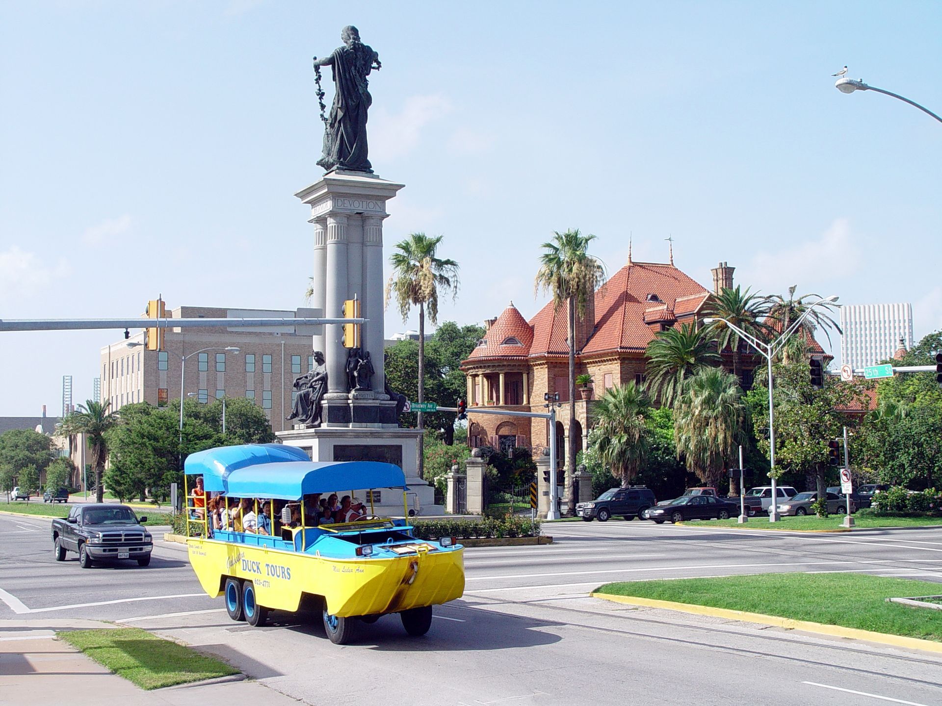 A yellow and blue amphibious vehicle is driving down a street