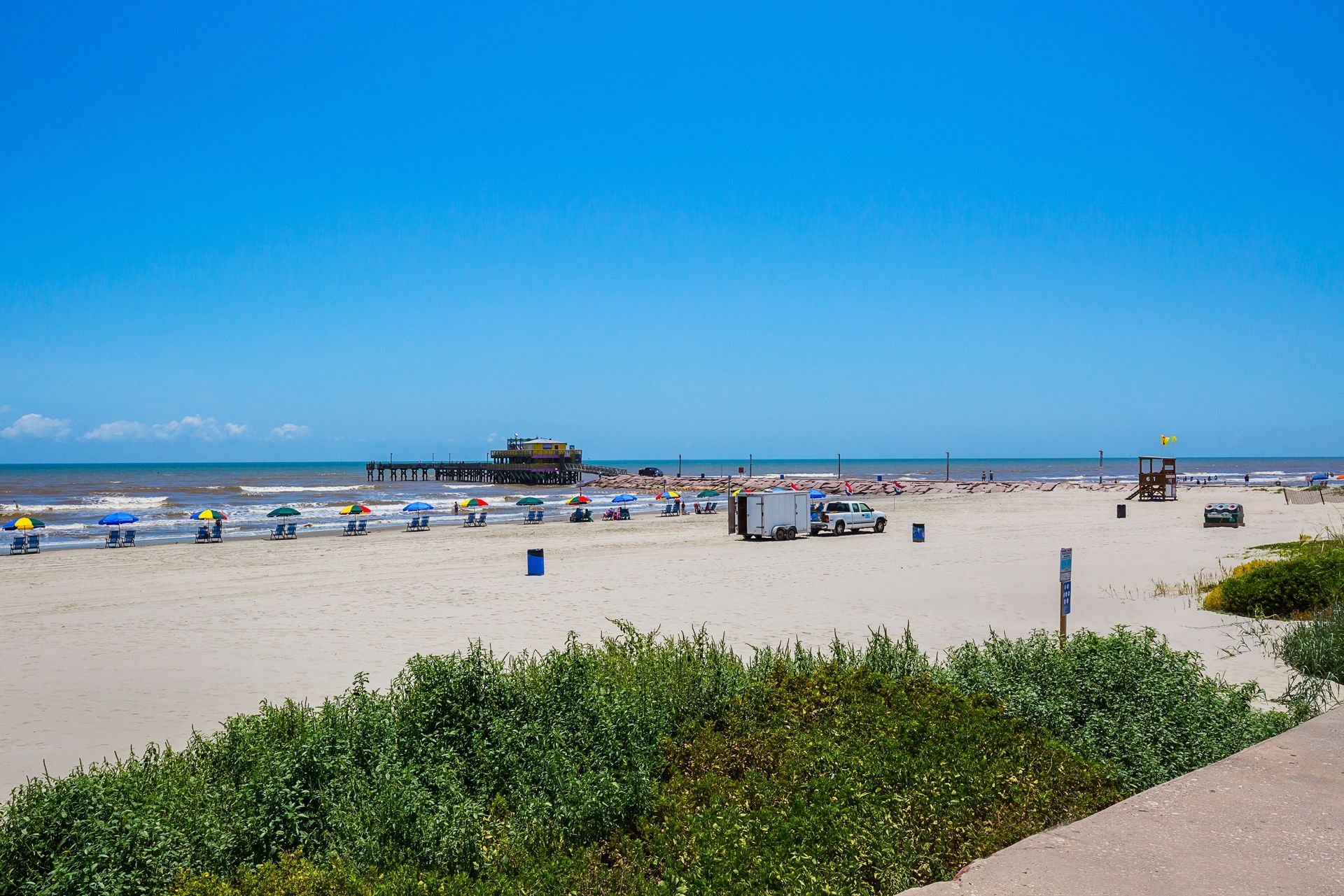A beach with a lot of people and umbrellas on a sunny day.
