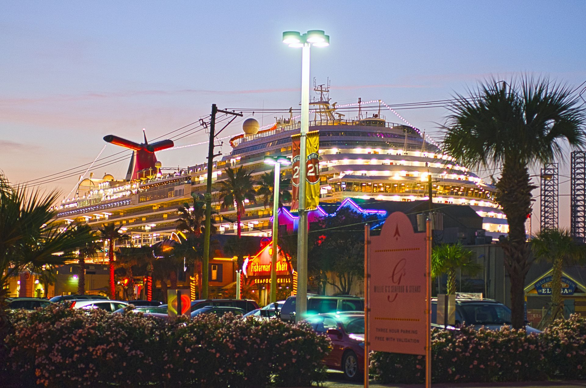 A large cruise ship is lit up at night in a parking lot