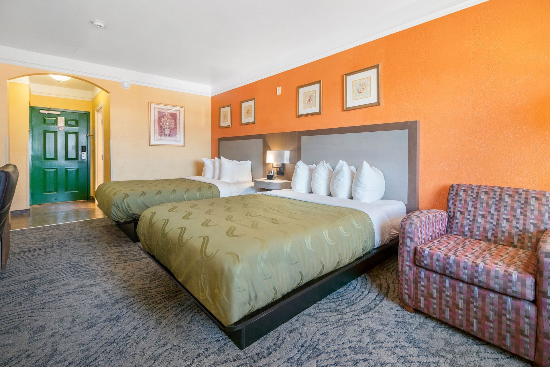 A hotel room with two beds and a chair.