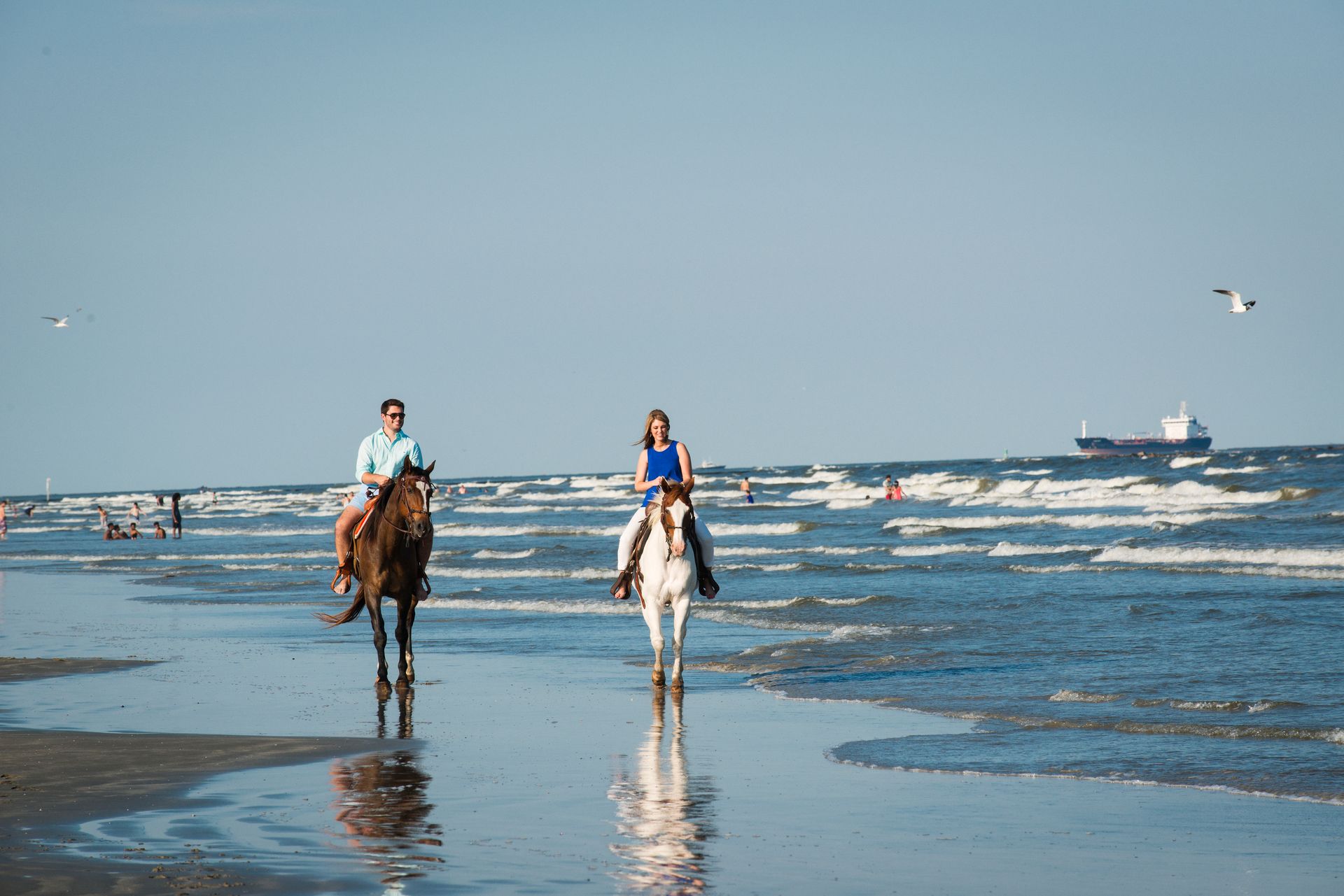 Two people are riding horses on the beach.