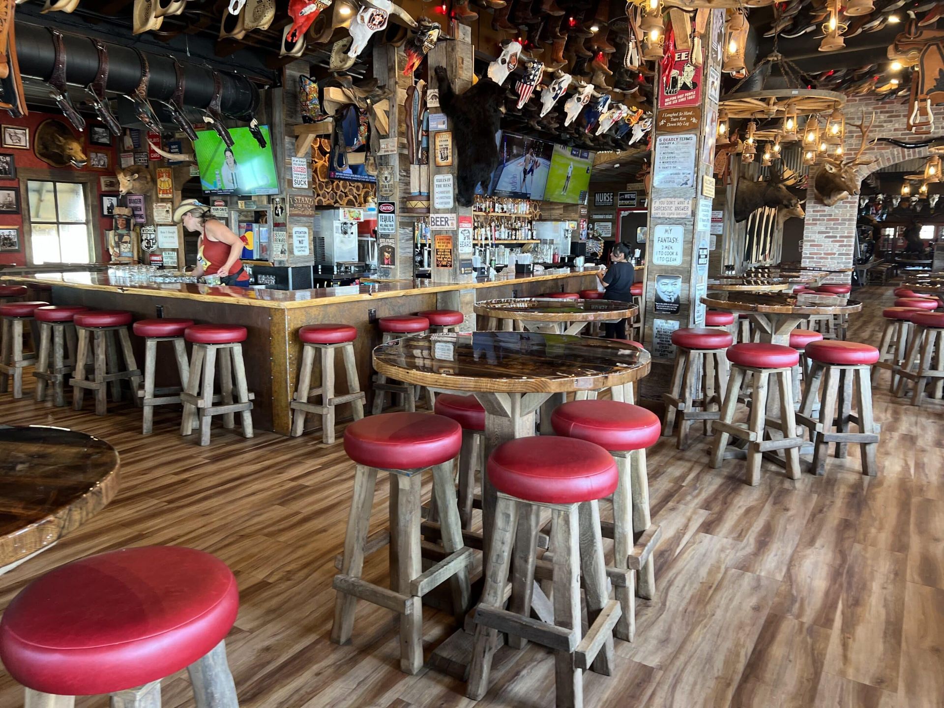 A restaurant with tables and stools and a bar.