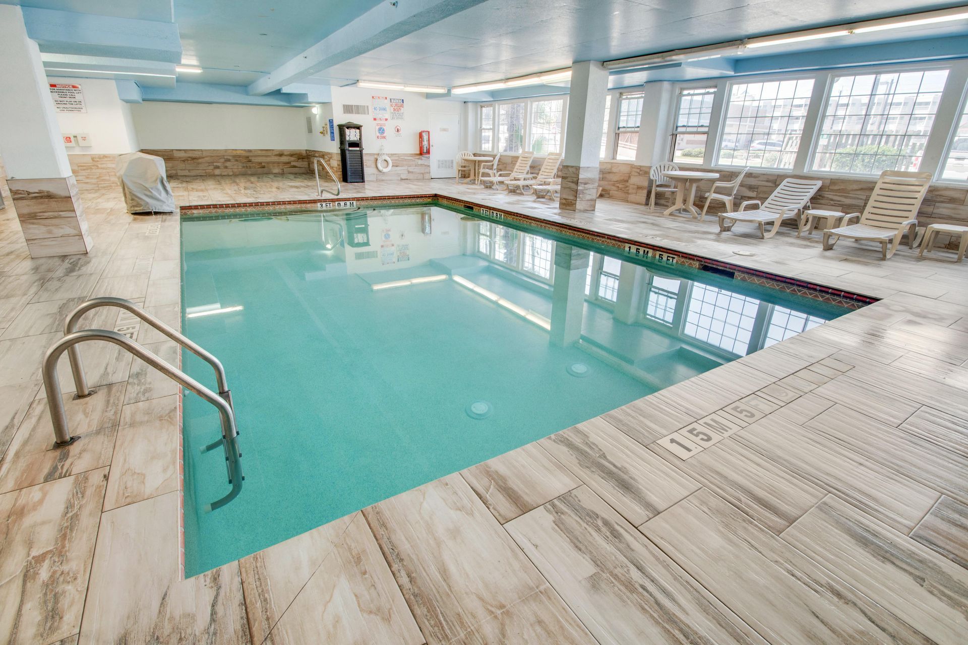 There is a large indoor swimming pool with chairs around it.