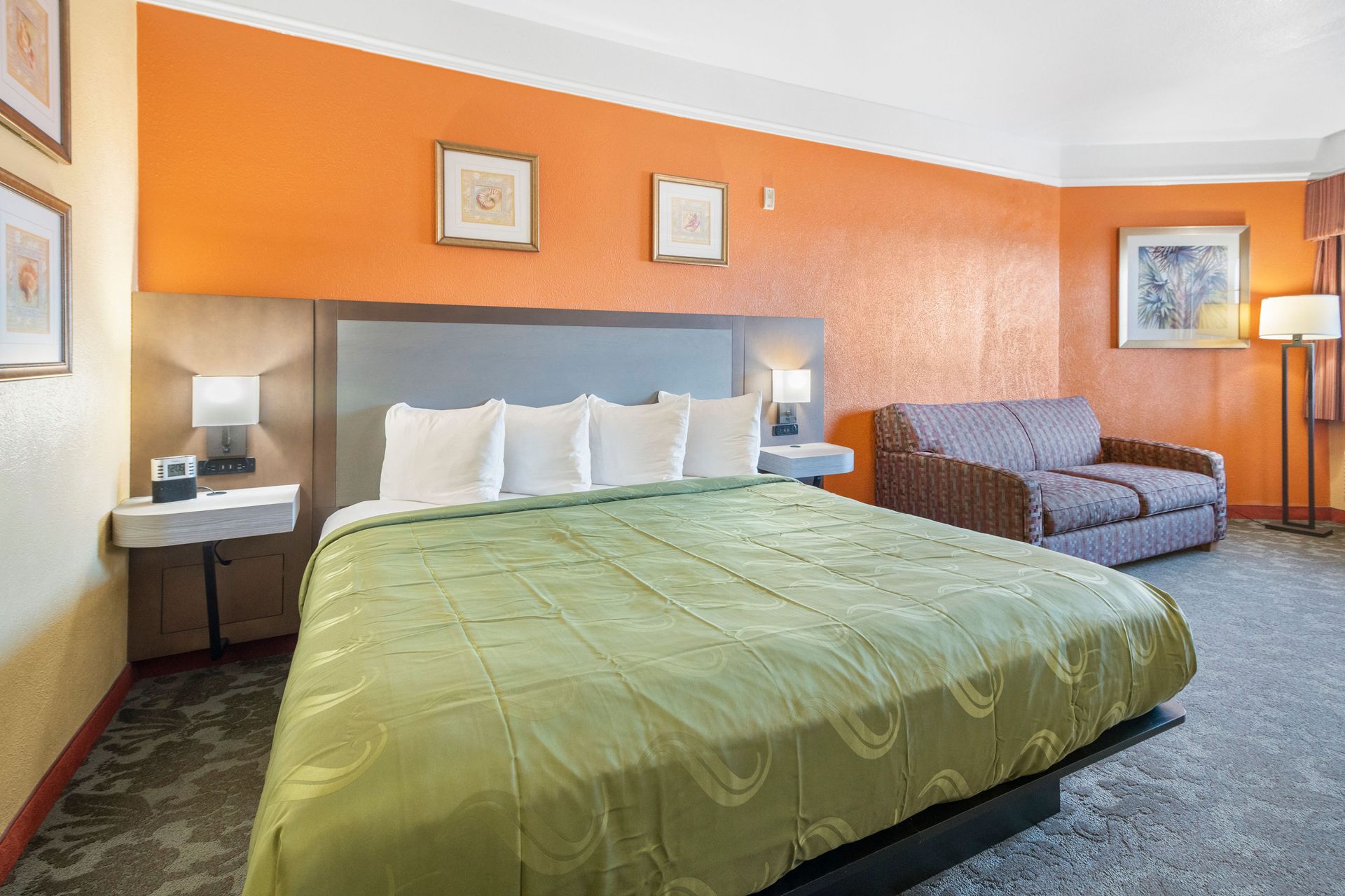 A hotel room with a king size bed and a couch.