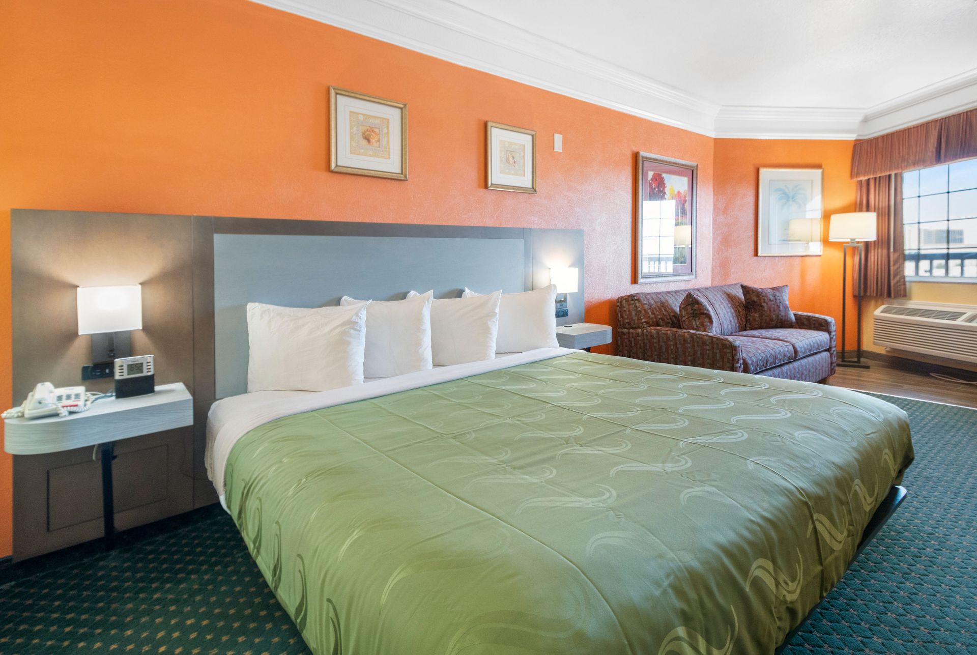 A hotel room with a king size bed and a couch.