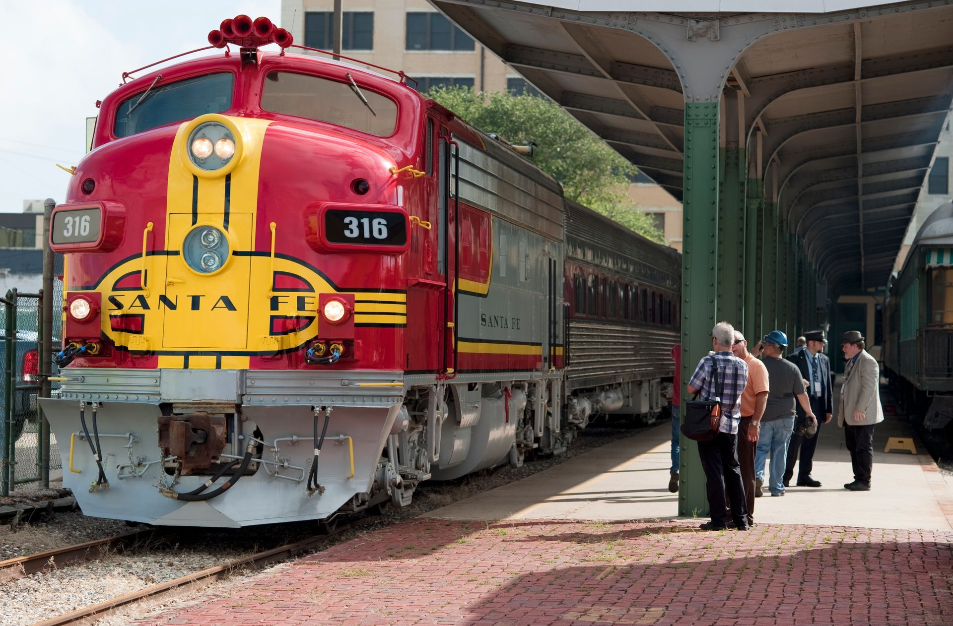 A red train with the number 316 on the front is parked at a train station.