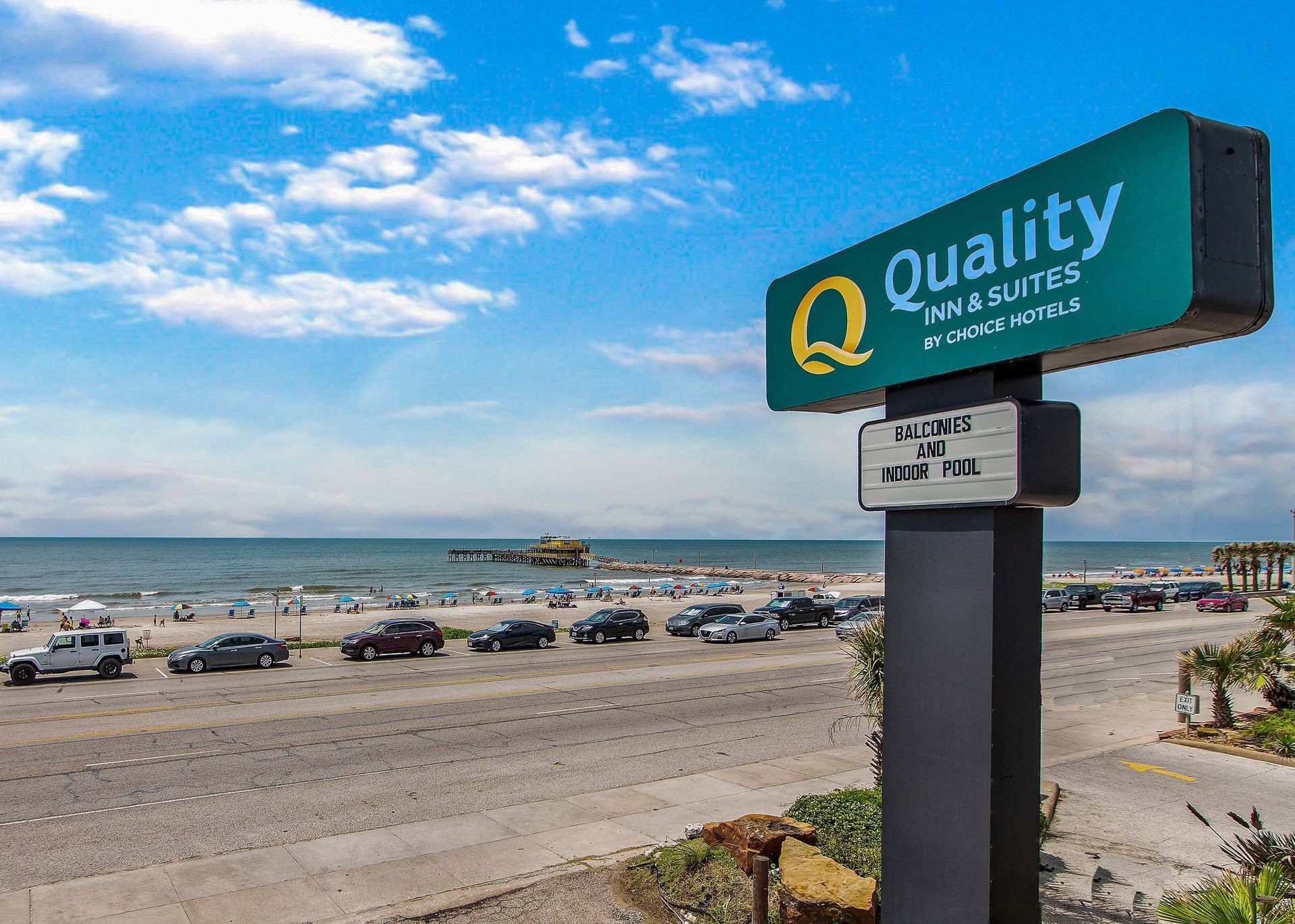 A quality inn and suites sign is sitting on the beach.
