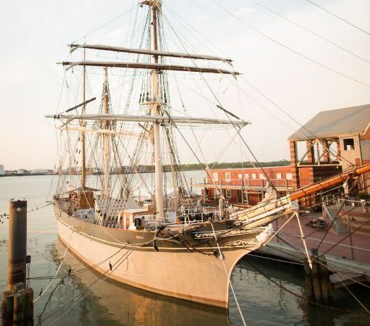 A large sailboat is docked at a dock in the water.