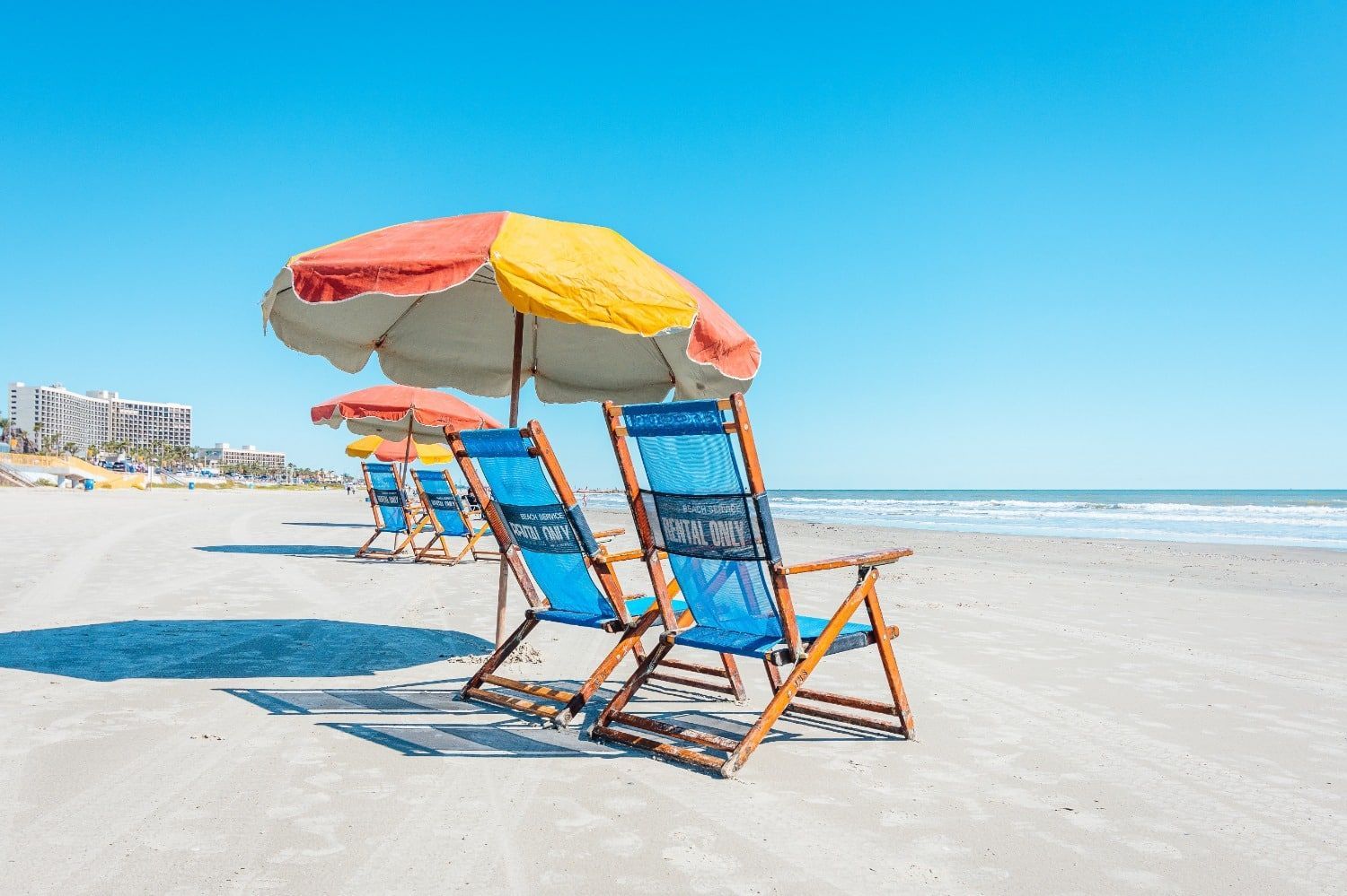 A row of beach chairs with umbrellas on the beach.