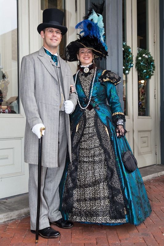 A man in a top hat and a woman in a blue dress are posing for a picture.