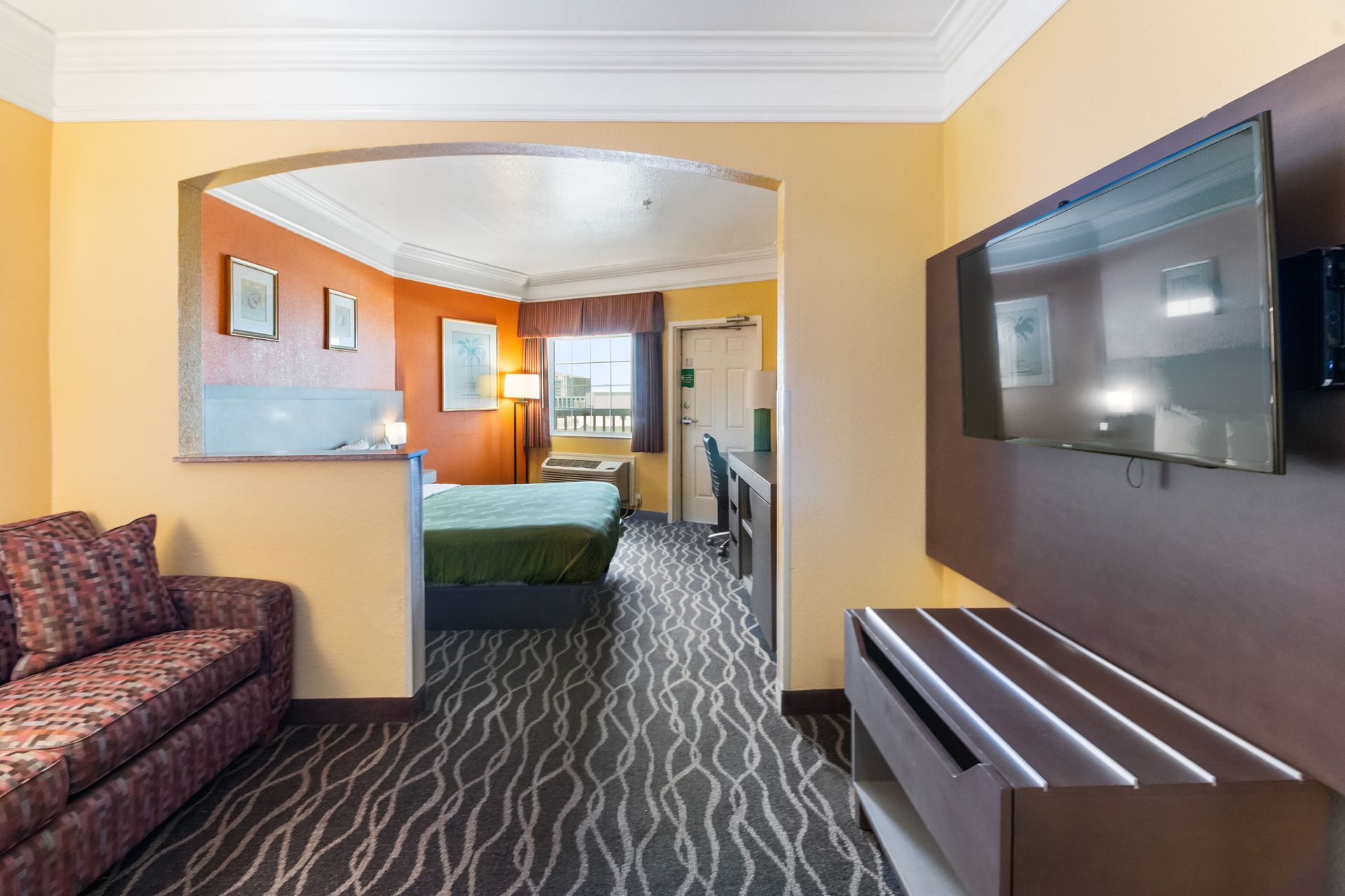 A hotel room with a couch , table , and television.