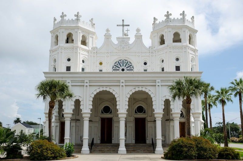 A large white church with palm trees in front of it