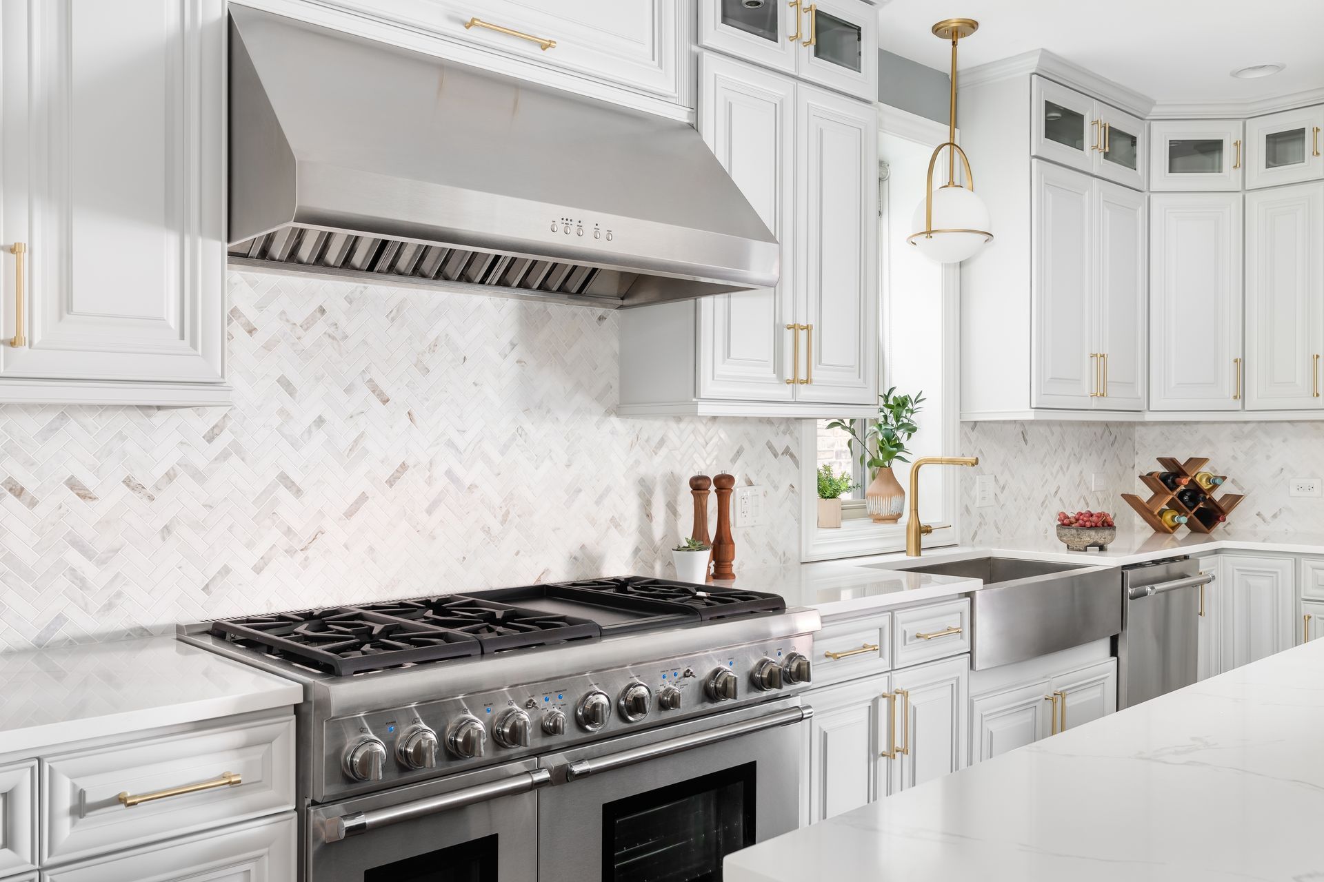 Stainless steel range with hood in a white kitchen with gold accents.